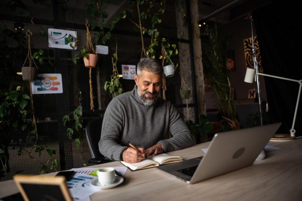 Entreprenör planerar företagets nya hemsida med dator och anteckningsbok