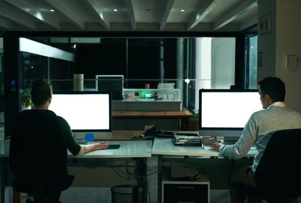 Webbutvecklare arbetar tillsammans vid flera datorskärmar på ett kontor